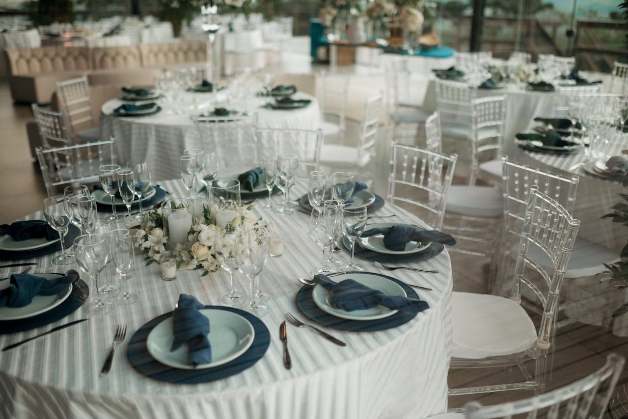 Wedding reception tables set with place settings and clear chairs